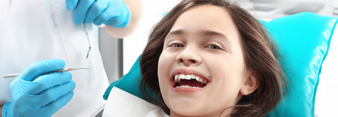 little girl at a pediatric dentist getting fluoride treatment