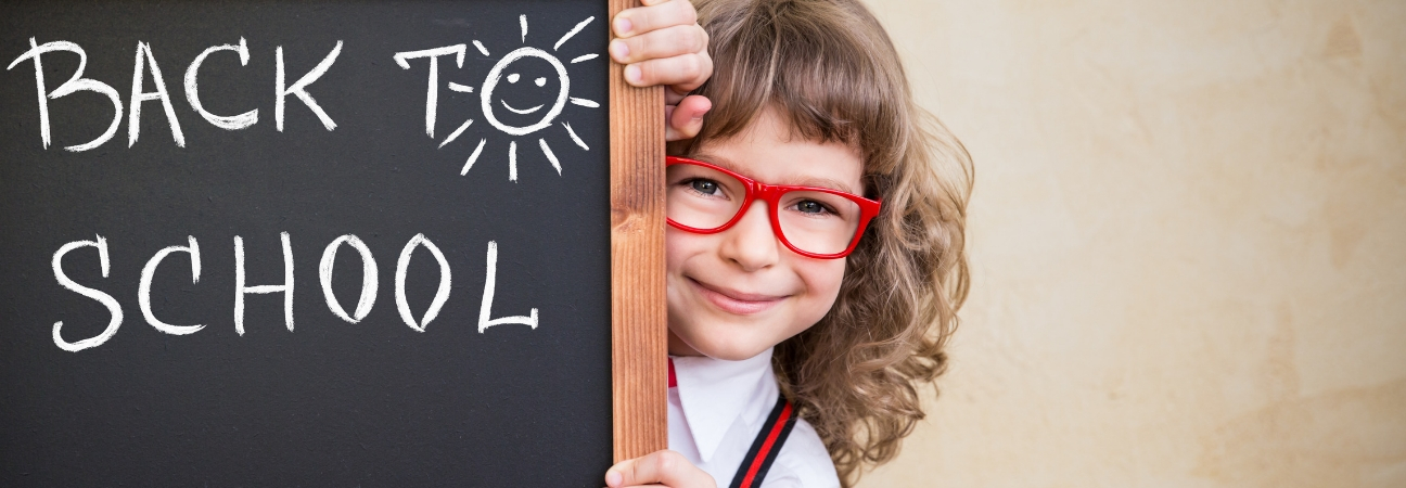 Girl in red glasses standing beside back-to-school chalkboard